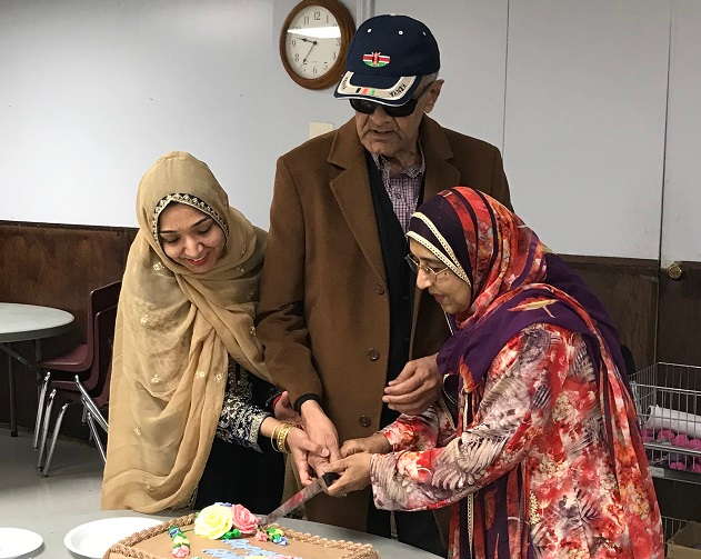 10 Little Ways to Show Love to an Elderly Parent Every Day (2) 10 Little Ways to Show Love to your Elderly Parents Every Day, Nargis with her mother and father, all dressed in traditional attire, cutting a decorated cake together in a communal indoor setting.